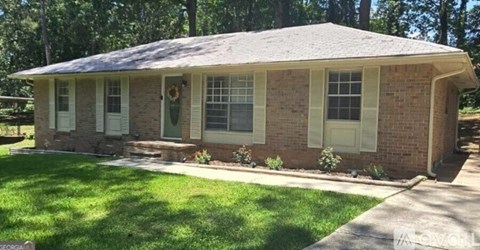 A small house with a green lawn in front.