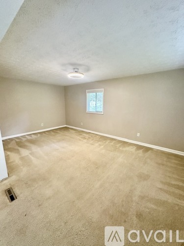 A room with a window and carpeted floor.