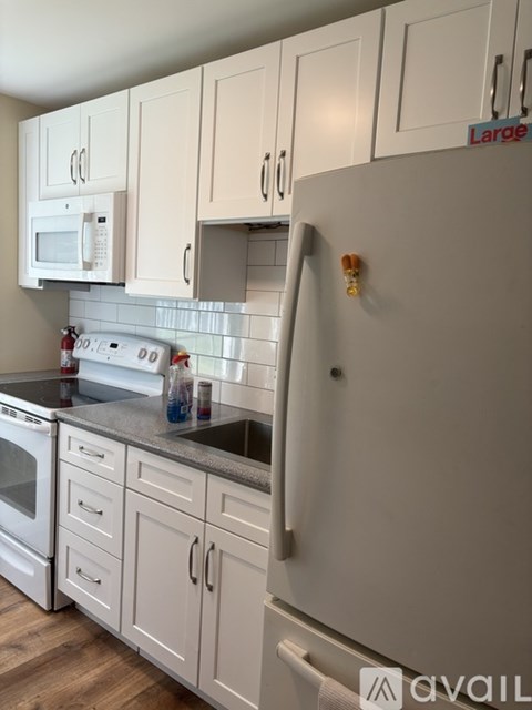 A kitchen with white cabinets and a white refrigerator with a red label on it.