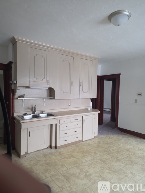 A kitchen with a sink, cabinets, and a counter.