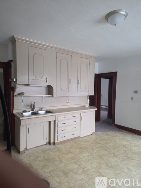 A kitchen with a sink, cabinets, and a counter.