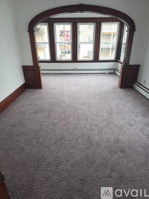A carpeted room with a large arched window.