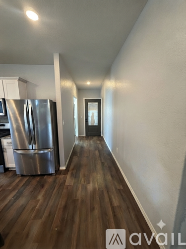 A kitchen with a stainless steel refrigerator and wooden floors.