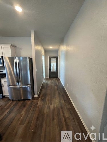 A kitchen with a stainless steel refrigerator and wooden floors.