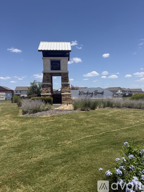 A small tower with a sign that reads "Minding Brook" stands in a grassy field.