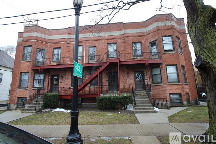 A red brick building with a green sign on a black pole.