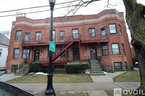 A red brick building with a green sign on a black pole.