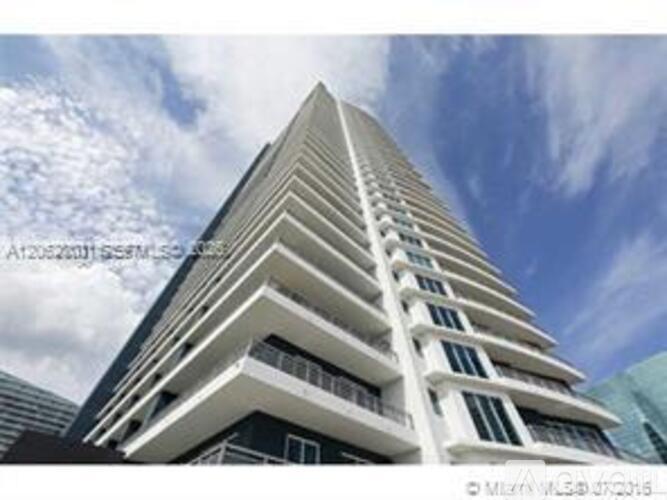 A tall white building with balconies on each floor.