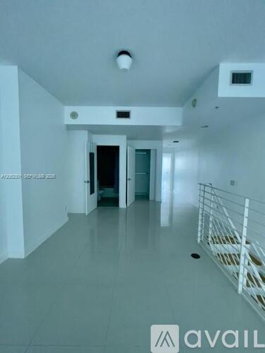 A spacious hallway with a staircase on the right and a door at the end.