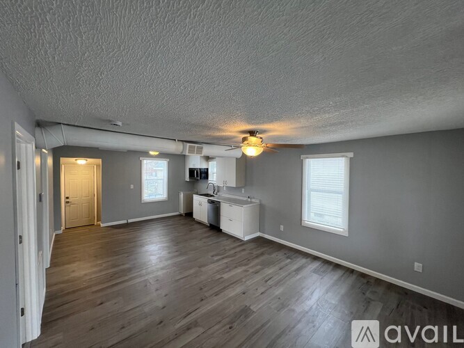 A spacious room with a kitchenette and wooden floors.