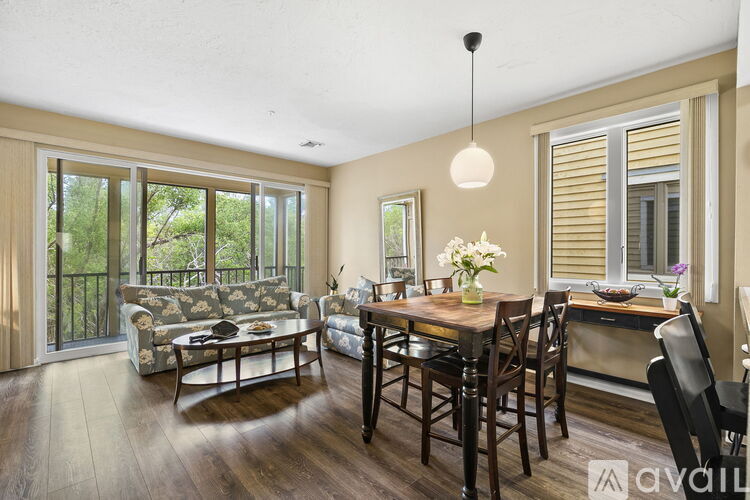 A dining room with a table set for four and a couch with a cushion that has a floral pattern.