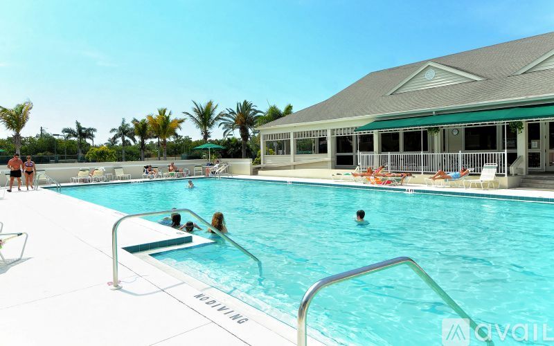A pool with people swimming and lounging chairs.