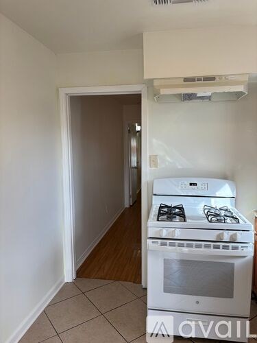A white kitchen with a stove and a doorway.