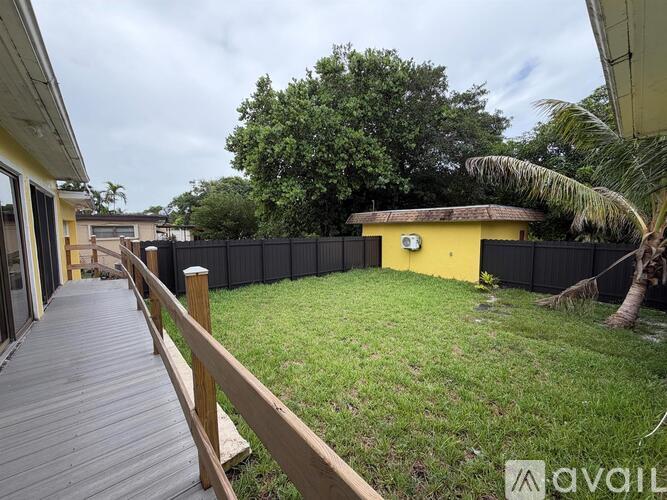 A backyard with a wooden deck and a yellow building.
