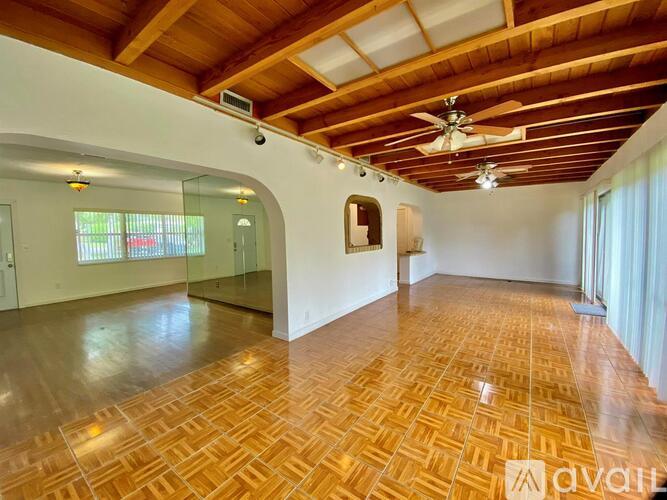 A spacious room with wooden flooring and a ceiling fan.