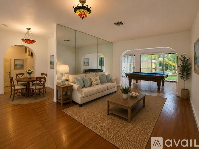 A living room with a white sofa, wooden coffee table, and a large mirror.