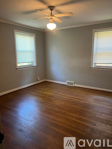 A room with a ceiling fan and wooden flooring.