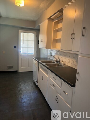 A kitchen with white cabinets and a black countertop.