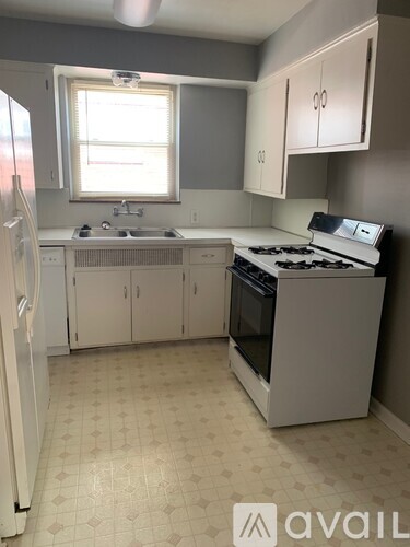 A kitchen with a white fridge, white cabinets, and a white stove top oven.