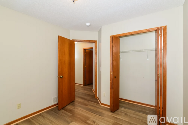 A room with a white wall and a wooden floor with a door and a mirror.
