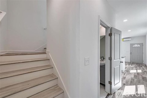 A hallway with a staircase on the left and a door on the right.
