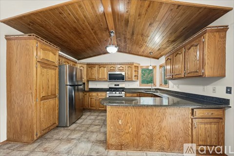 A kitchen with wooden cabinets and a refrigerator.