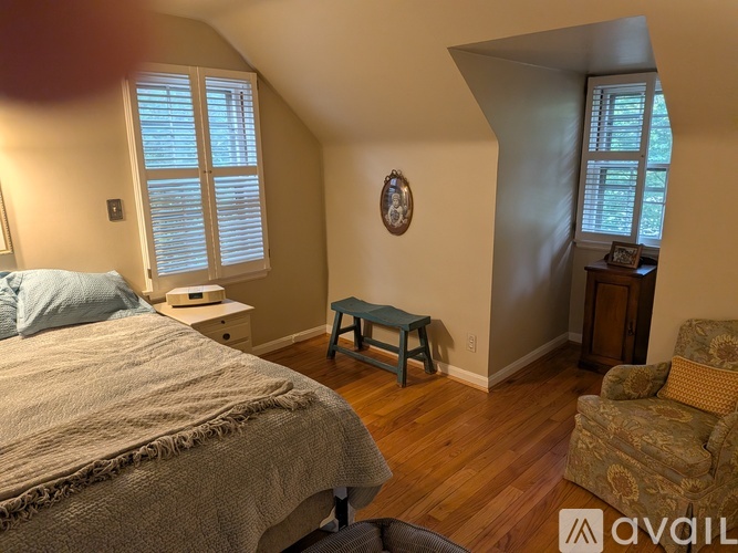 A bedroom with a bed, chair, and window.