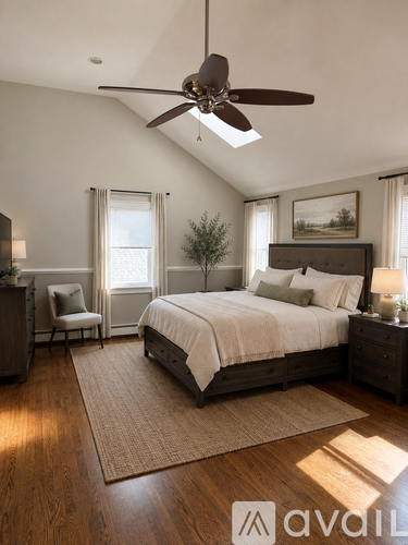A bedroom with a large bed, a ceiling fan, and a rug on the floor.