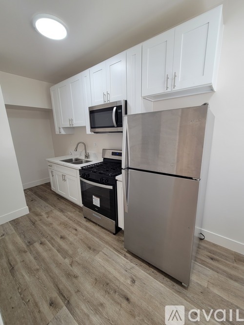 A kitchen with white cabinets and a stainless steel refrigerator.