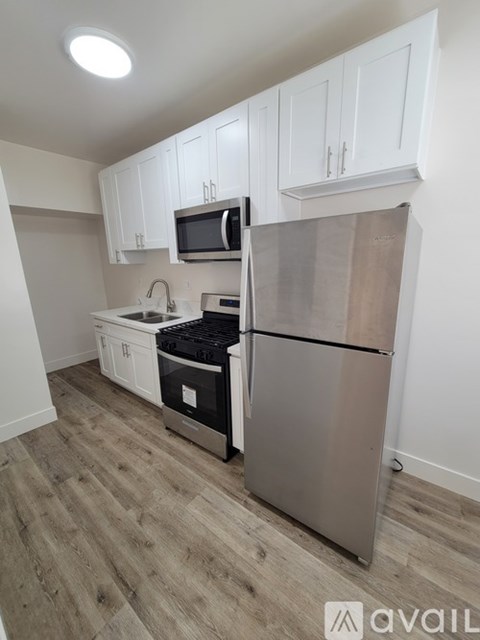 A kitchen with white cabinets and a stainless steel refrigerator.