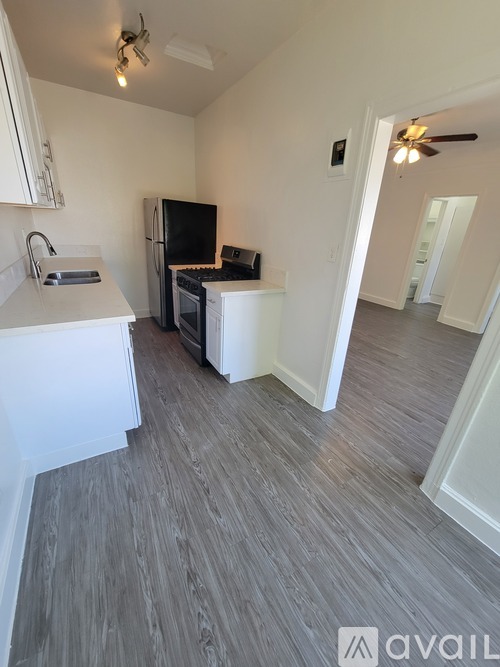 A kitchen with white cabinets and a black fridge.