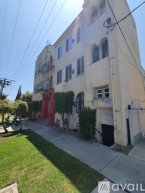 A white building with a red door and a balcony.
