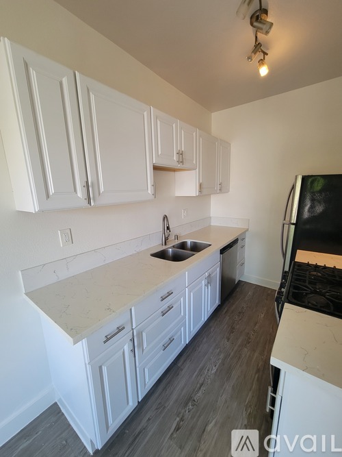 A kitchen with white cabinets and a marble countertop.