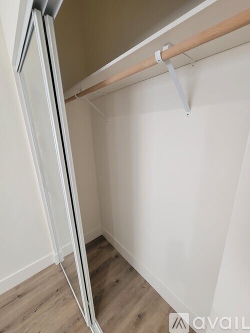 A white refrigerator is installed in a kitchen with a white wall and wooden floor.