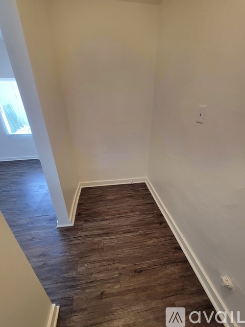 A hallway with wooden floors and white walls.