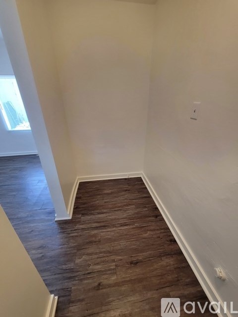 A hallway with wooden floors and white walls.