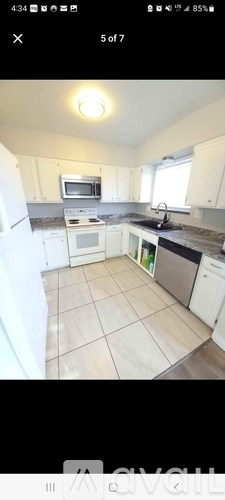 A kitchen with white cabinets and a black countertop.