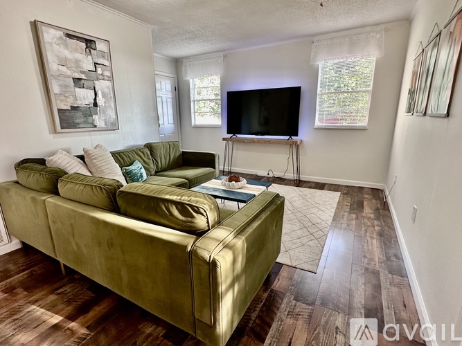 A living room with a green couch and a television on a stand.