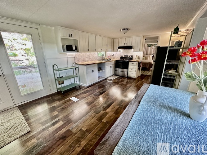 A kitchen with white cabinets and a wooden floor.