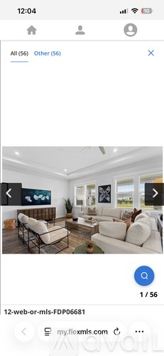 A modern living room with white furniture and a large window.