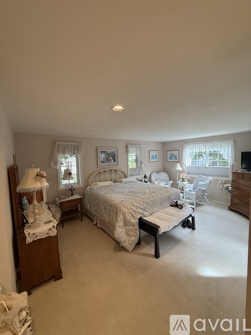 A bedroom with a large bed, a nightstand with a lamp, and a dresser with a mirror.