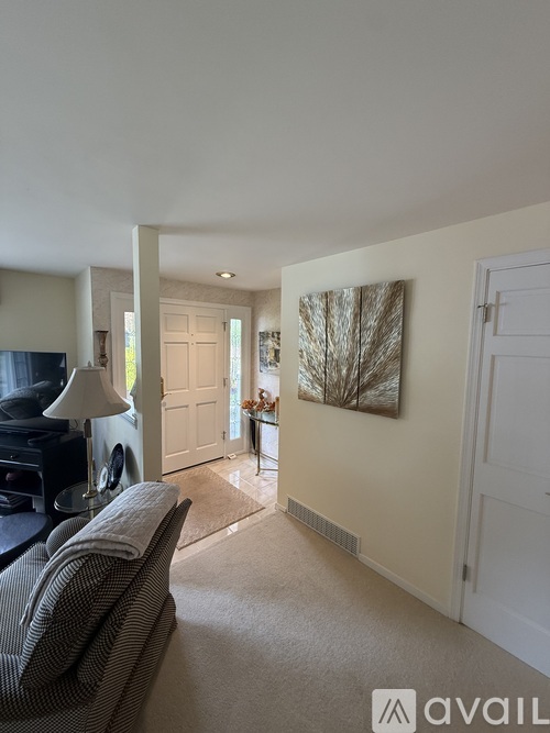 A living room with a grey couch and a painting on the wall.