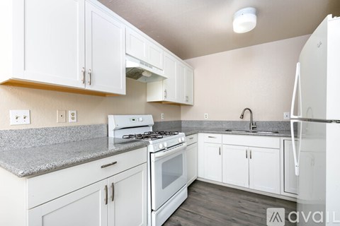 A kitchen with white cabinets and appliances.