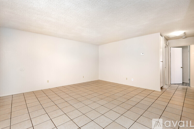 A spacious room with tiled flooring and white walls.
