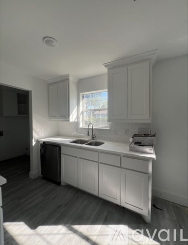 A kitchen with white cabinets and a window above the sink.