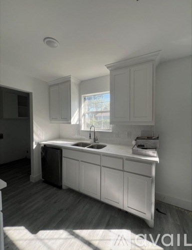 A kitchen with white cabinets and a window above the sink.