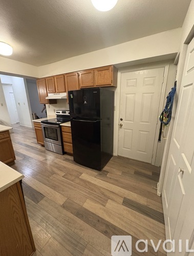 A kitchen with wooden cabinets and a black refrigerator.
