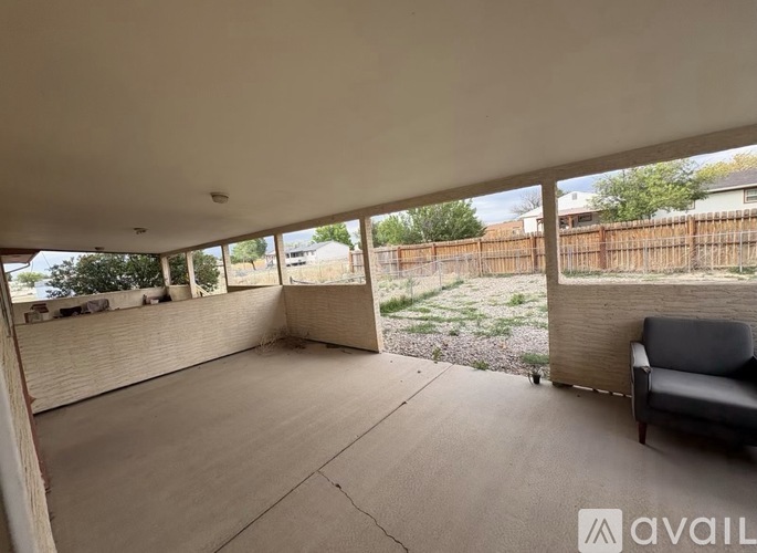 A room with a couch and a window overlooking a fence and trees.
