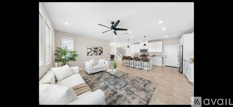 A spacious living room with a white sofa set and a rug.