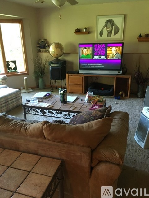 A living room with a brown couch and a television playing a show.